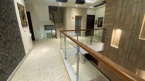 A modern interior with a glass railing, a staircase, and a patterned wall.