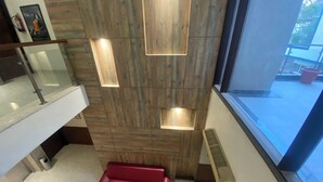 A modern interior with a wooden wall, a red bench, a glass railing, and a window with a view.