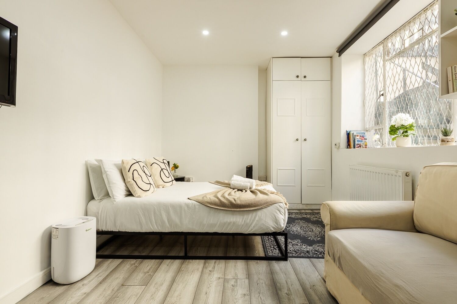 Ein Schlafzimmer mit Bett, Sofa, Heizkörper, Fenster mit Blick und Kleiderschrank.