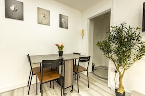 A dining area with a table and chairs, a potted plant, and wall-mounted artwork.