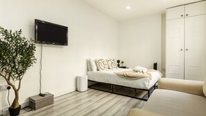 Een moderne slaapkamer met een bed, nachtkastje en een aan de muur bevestigde televisie.