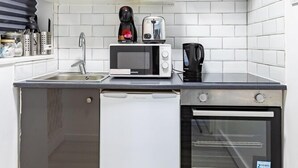 A compact kitchen with a microwave, toaster, coffee maker, and a small refrigerator. - Cozy Flat Near Hyde Park! (Greater London)