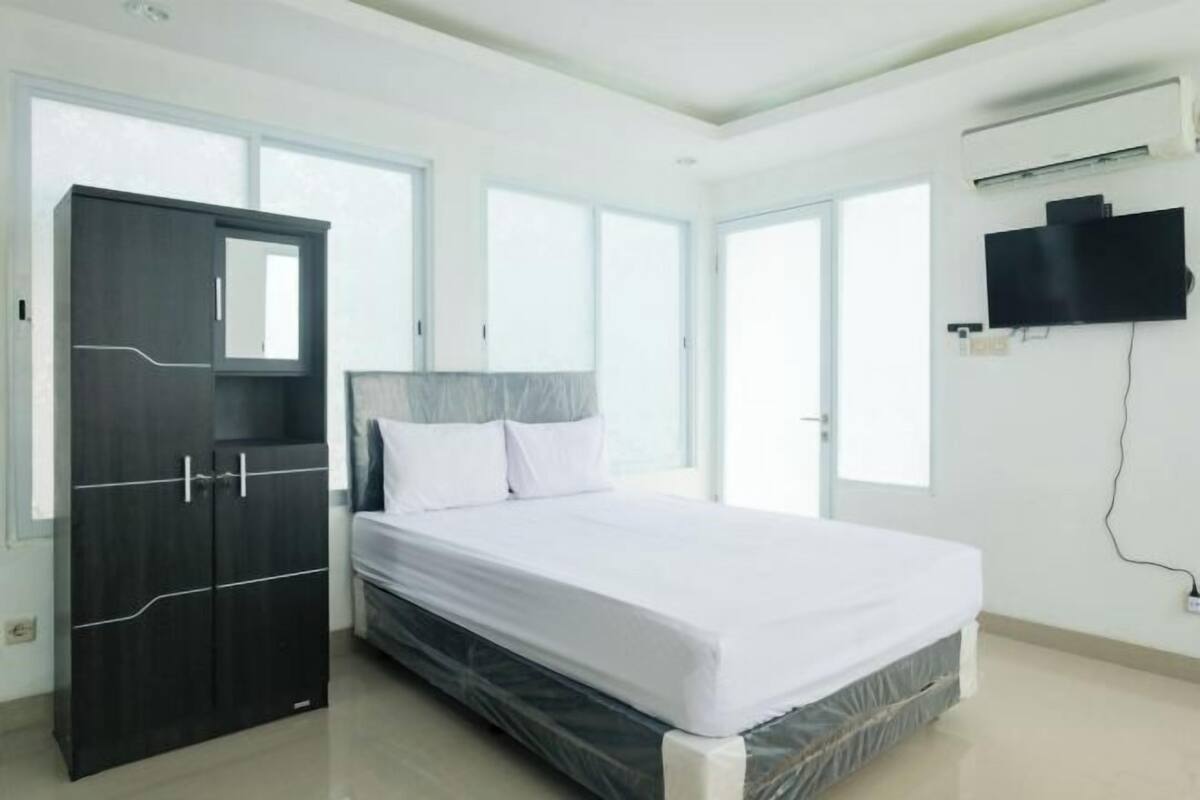 Quarto com cama, guarda-roupa e televisão na parede.