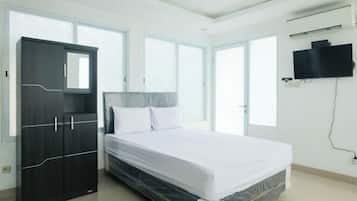 A bedroom with a bed, a wardrobe, and a TV mounted on the wall.