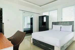Een moderne hotelkamer met een groot bed, een stoel, een kledingkast en een schuifdeur naar een badkamer.