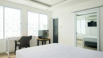 A modern hotel room with a large bed, a desk with a chair, a television, and a sliding door leading to a bathroom.