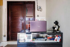 A room with a wooden door, a laptop on a glass table, and a camera on a tripod.