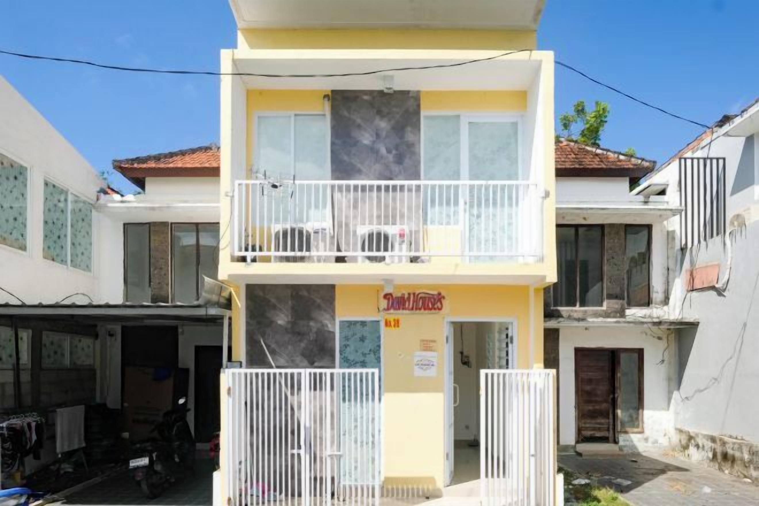 A two-story building with a yellow facade and a balcony.