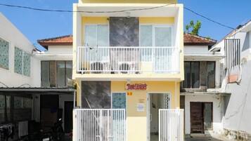 A two-story building with a yellow facade and a balcony.