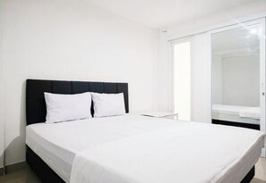 Een hotelkamer met een bed, nachtkastje en een schuifdeur naar een badkamer.