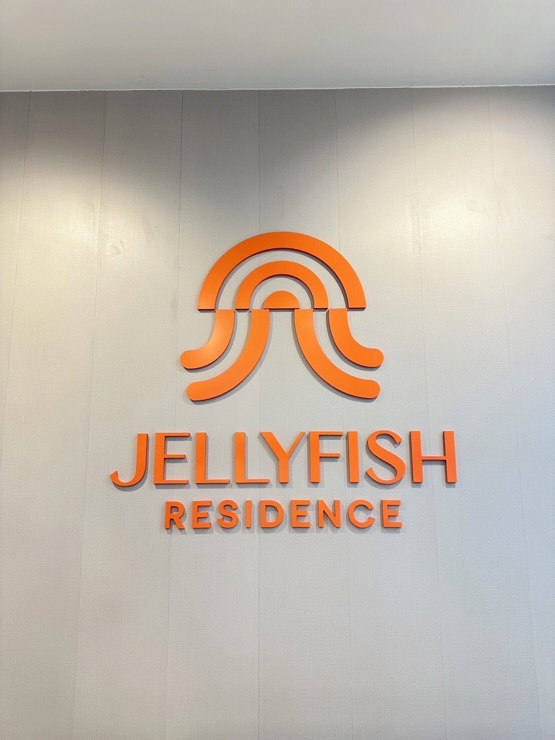 Un letrero para Jellyfish Residence con un logotipo estilizado en la parte superior.