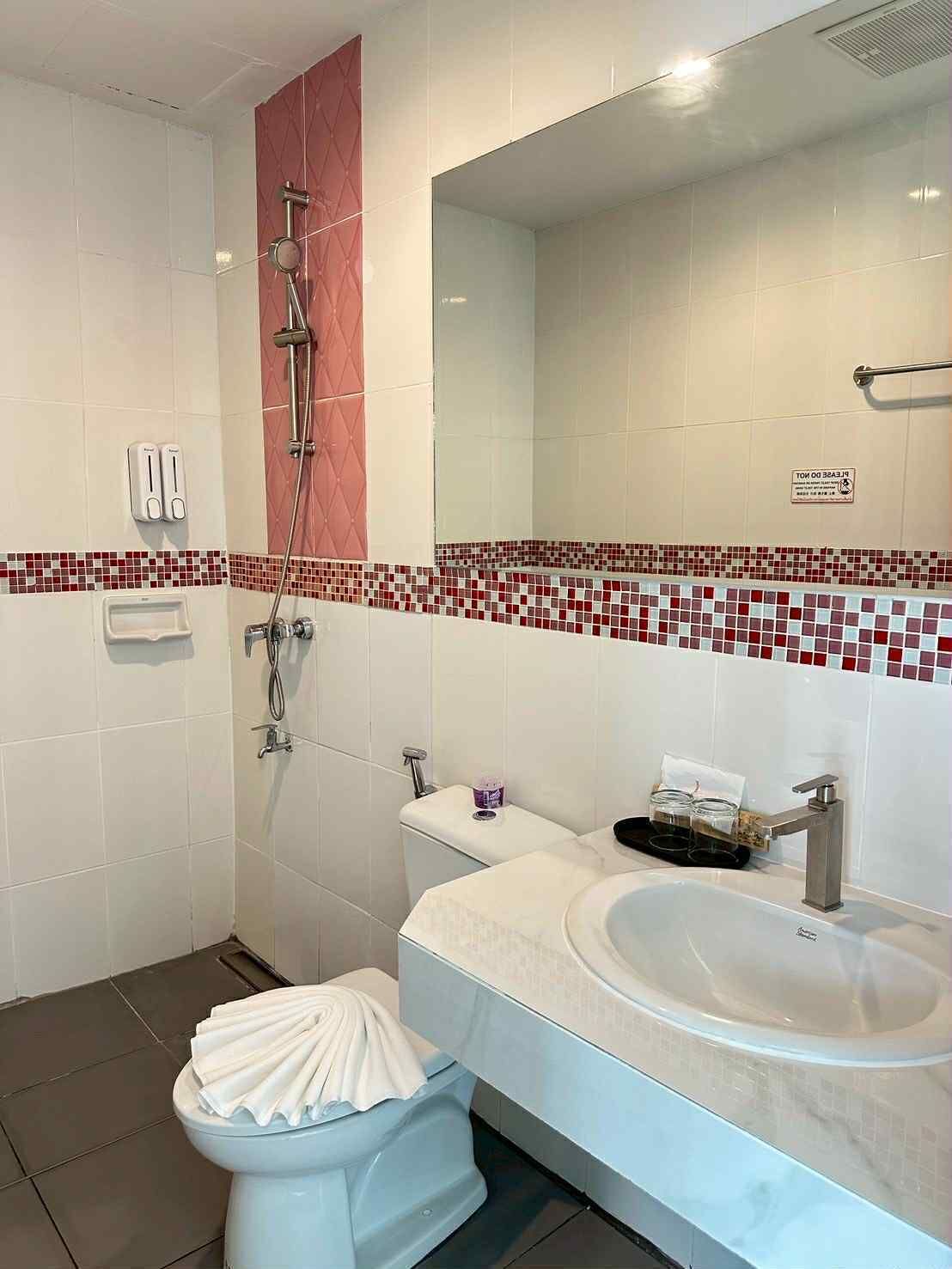 A bathroom with a shower, toilet, sink, and a mirror.