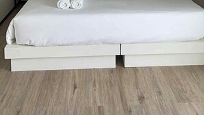 Un dormitorio moderno con una cama grande, dos mesitas de noche, una lámpara de techo y una obra de arte enmarcada en la pared.