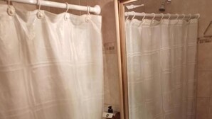 Ein Badezimmer mit Duschvorhang, Waschbecken, Spiegel und Seifenspender.