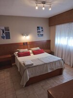 Quarto de hotel com uma cama grande, mesas de cabeceira, um painel de cabeceira de madeira e um lustre no teto.