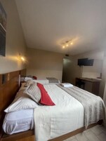 Habitación de hotel con dos camas, un escritorio, televisión de pantalla plana y ventilador de techo.