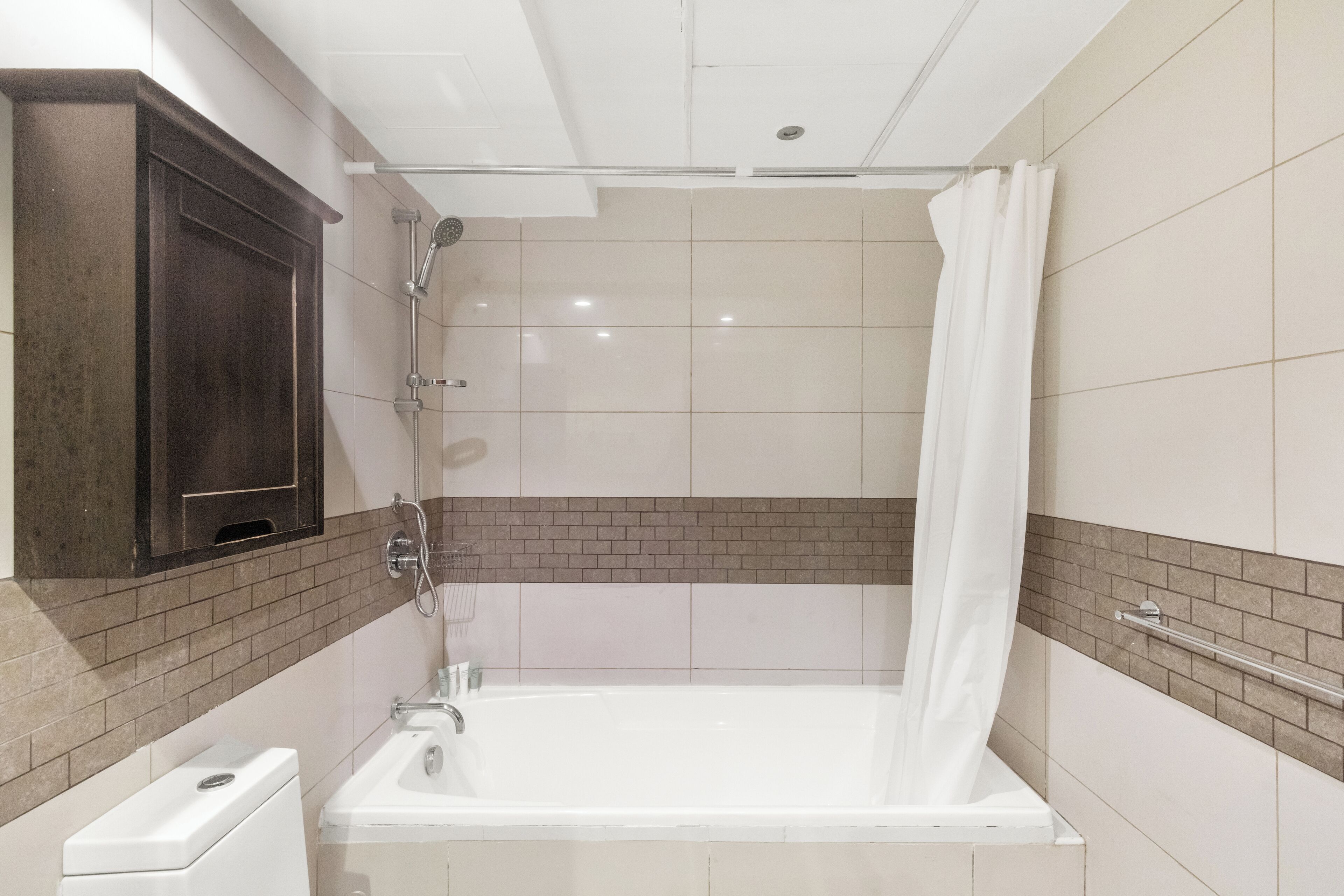 Et badeværelse med badekar, bruser og toilet.