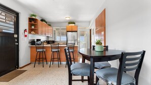 A compact kitchen with a dining area, featuring a refrigerator, stove, and bar stools.