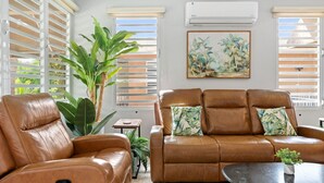 A living room with a brown leather sofa and armchair, a small table, and a large plant.