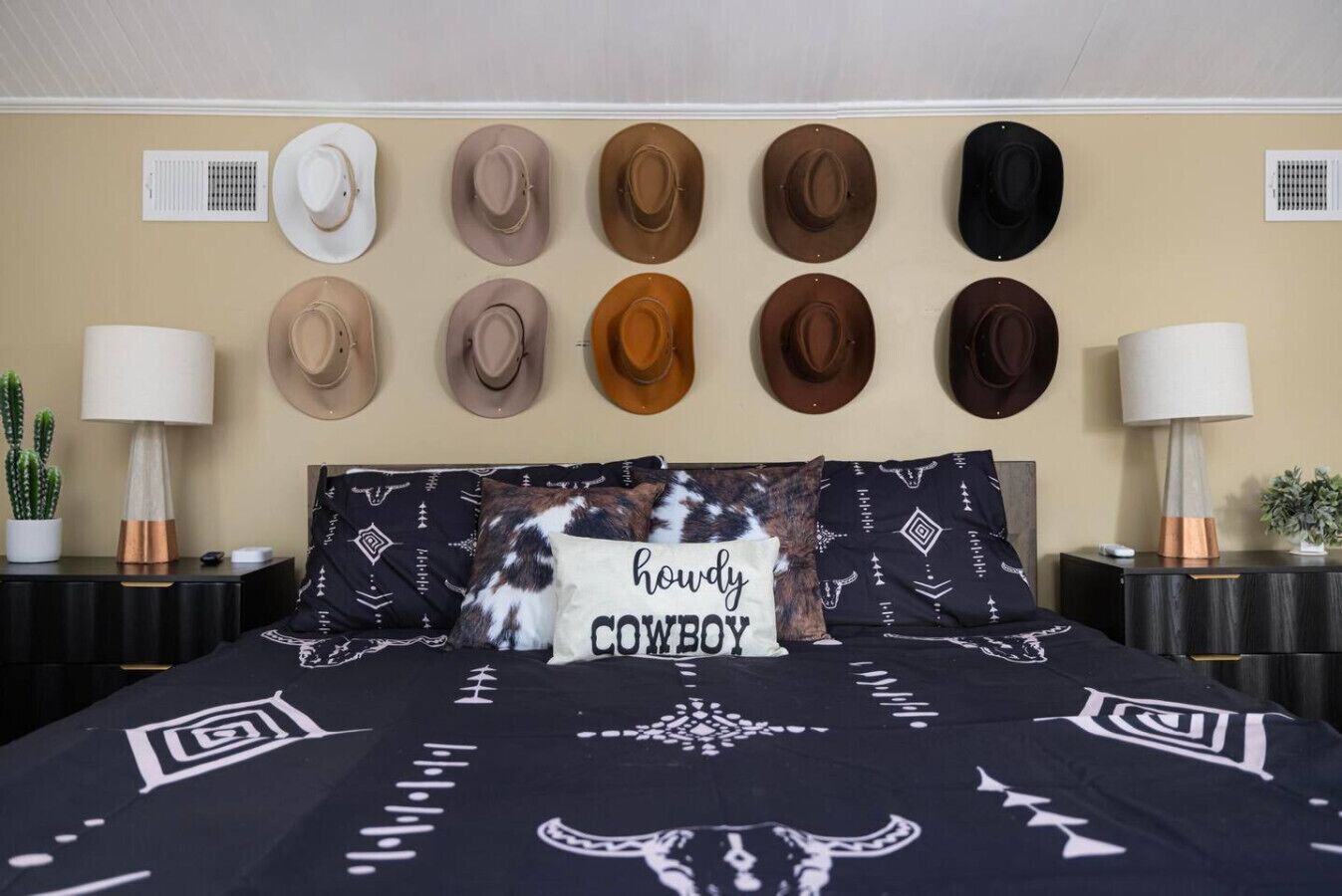 Ein Schlafzimmer mit Bett, Kissen und einer Wandgalerie voller Hüte.
