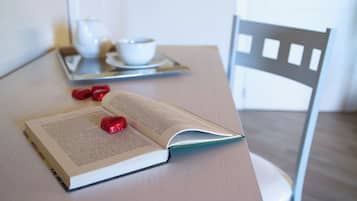 An open book on a table with a tray containing a teapot and cups, and a chair.