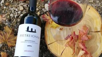 A bottle of Pietrejonne wine and a glass of red wine on a wooden surface with autumn leaves.