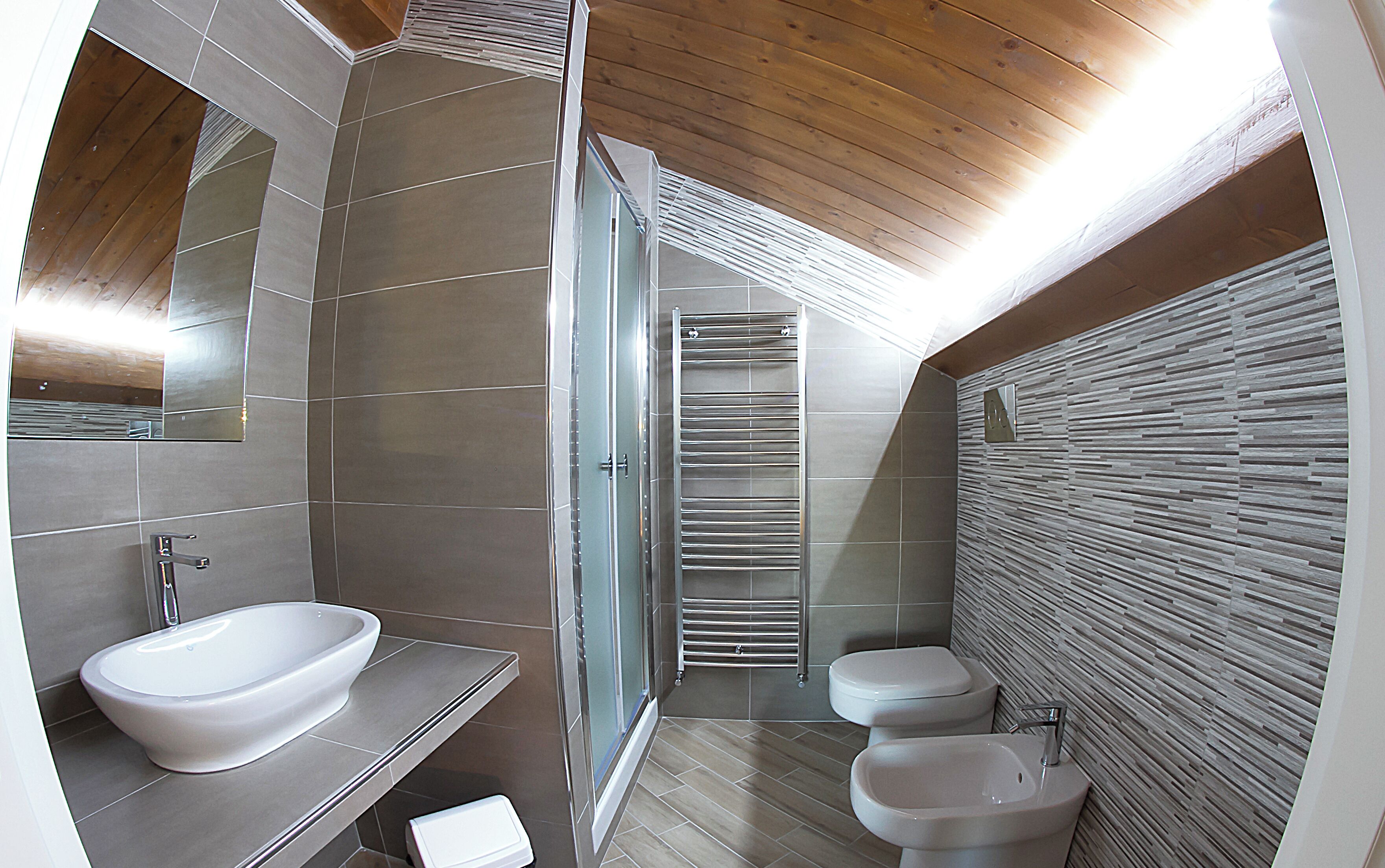 Un baño moderno con un espejo grande, dos lavamanos, una ducha y un inodoro.
