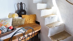 A rustic interior with a stone staircase, a wooden table with chairs, and a basket on the wall. - Bem Parece by Umbral (Albufeira)