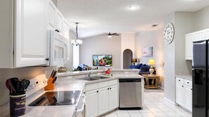A modern kitchen with white cabinets, stainless steel appliances, and a tiled floor. - SD2216MC – Golf-side 5-Bed Villa with Private Pool (Haines City)