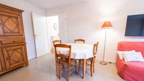 Un comedor con mesa y sillas, un aparador de madera, un sofá y una lámpara de pie.