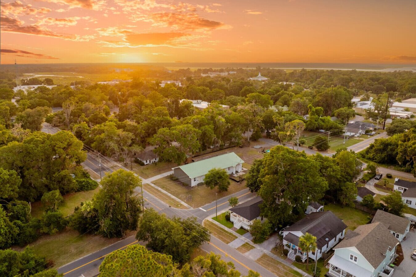 An aerial view of a residential area with houses, roads, and a large body of water in the background.