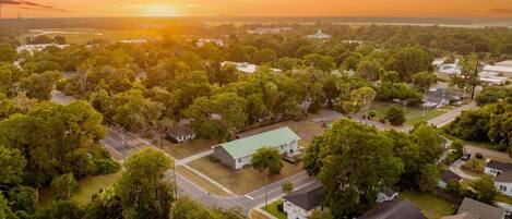 An aerial view of a residential area with houses, roads, and a large body of water in the background.
