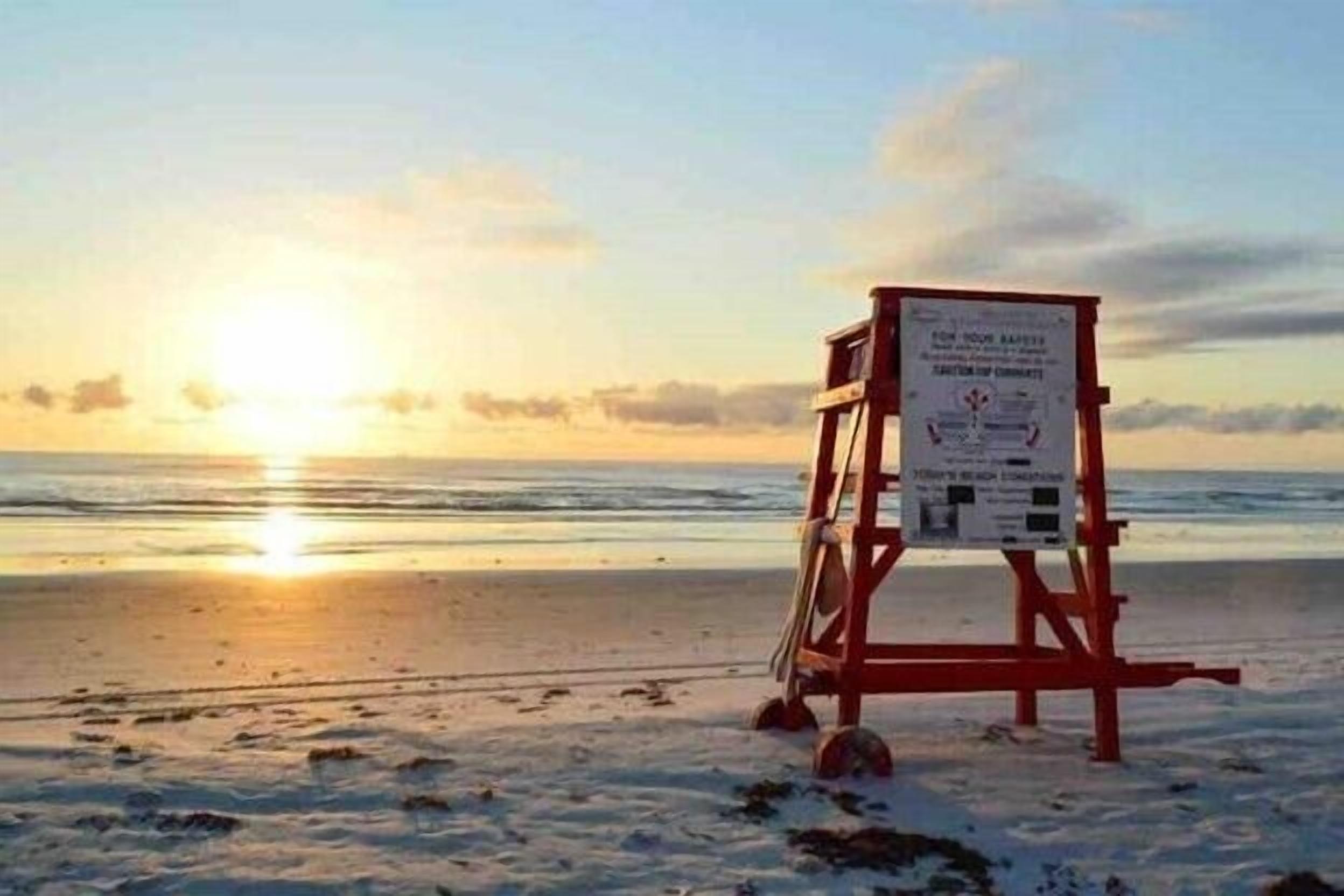 A lifeguard stand on a beach with a sunset in the background.