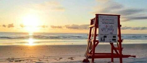 A lifeguard stand on a beach with a sunset in the background.