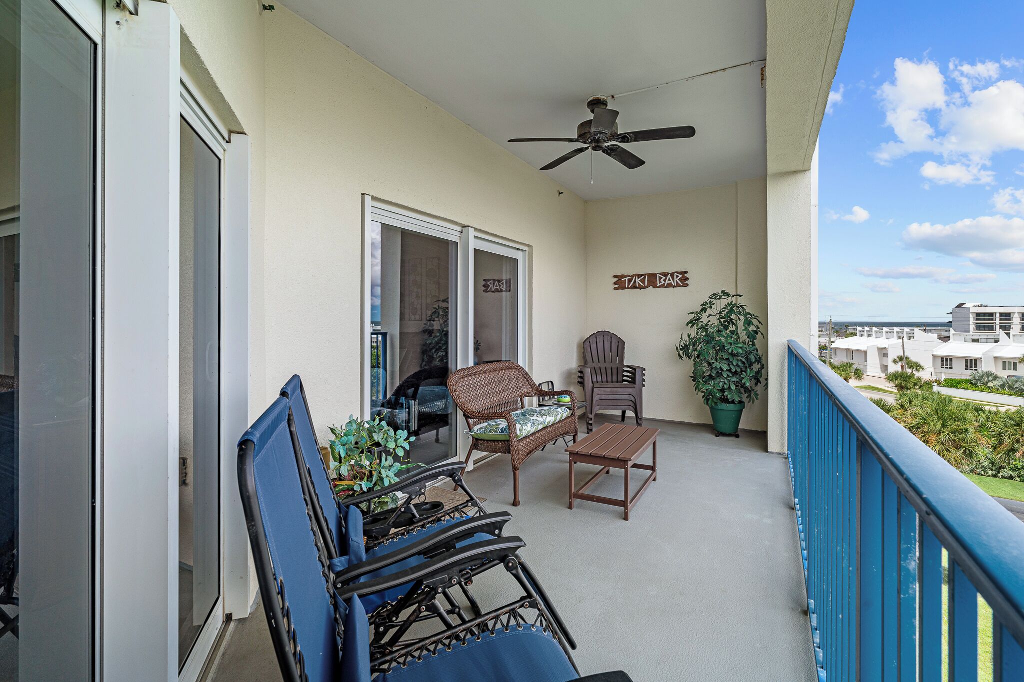 A balcony with wicker furniture, a ceiling fan, and a potted plant.