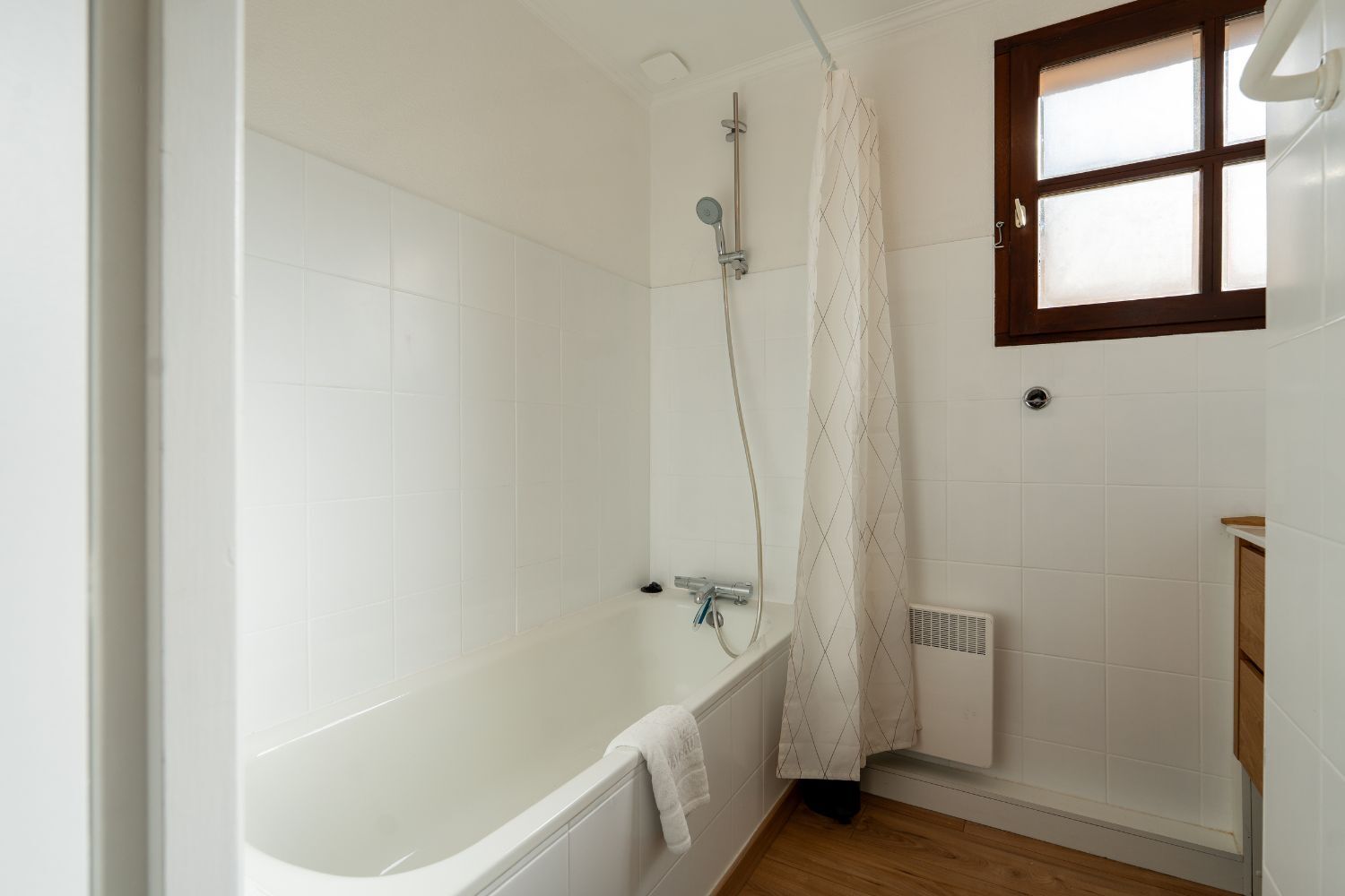 A bathroom with a bathtub, shower, and a window.