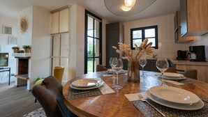 Un coin repas avec une table ronde en bois, dressée pour quatre personnes, entourée de chaises en cuir.