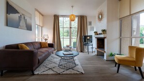 Un salon moderne avec un canapé, un fauteuil, une table basse et une cheminée.