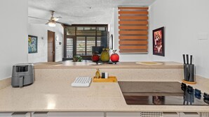 A modern kitchen with a built-in stove, a coffee maker, and a wooden tray with kitchen utensils. - Terrace Allows Pets Free Parking Otium (Fajardo)