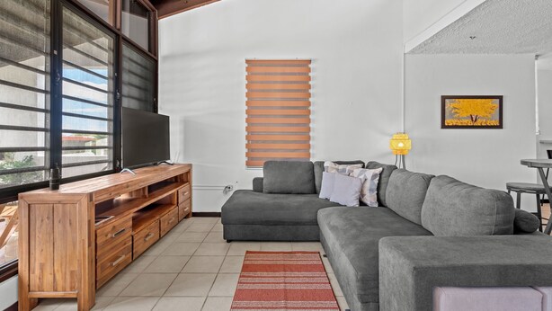 A modern living room with a grey sofa, wooden entertainment unit, and a large window. - Terrace Allows Pets Free Parking Otium (Fajardo)