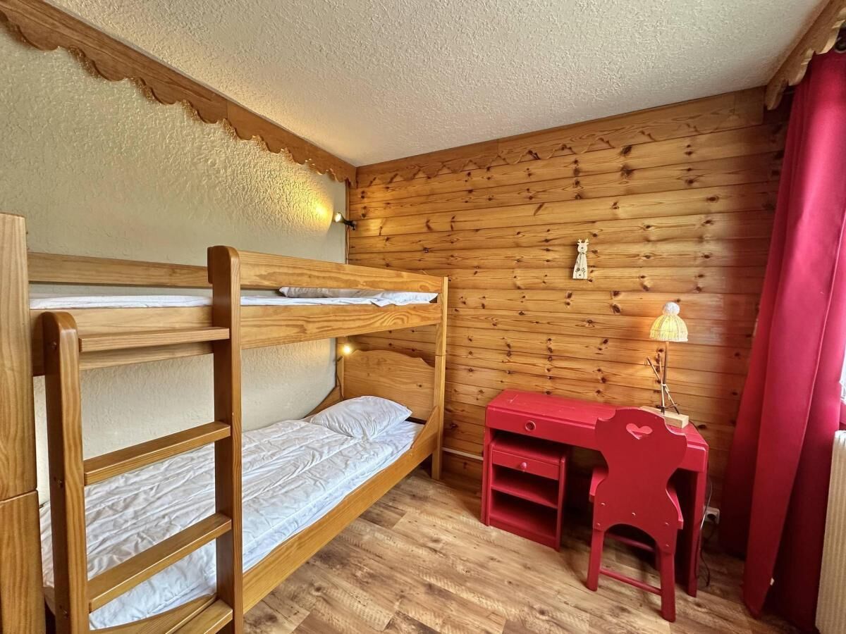 Dormitorio con literas, un escritorio de madera y una lámpara.