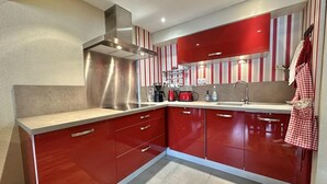 Una cocina moderna con armarios rojos, electrodomésticos de acero inoxidable y papel tapiz a rayas.