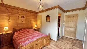 Un dormitorio con paneles de madera, una cama, mesitas de noche, un reloj de pared y una puerta.