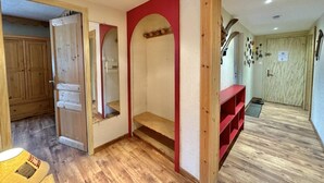 Una habitación con piso de madera, pared roja y puerta de madera.