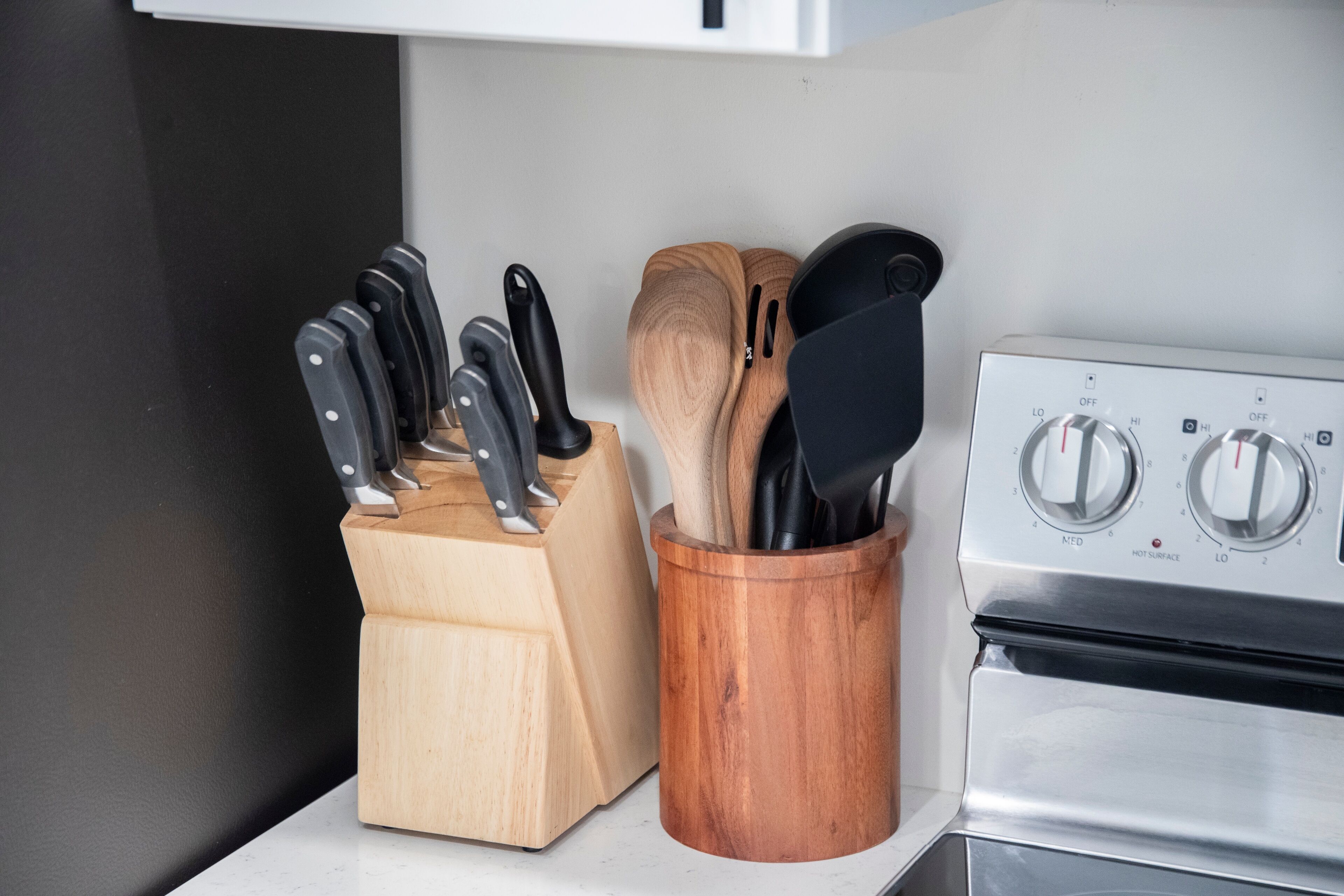 Una cocina con estufa, bloque de cuchillos y un utensilero de madera.