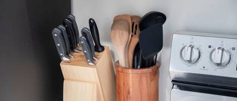 Una cocina con estufa, bloque de cuchillos y un utensilero de madera.