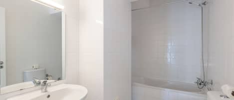 A bathroom with a sink, mirror, toilet, bidet, and bathtub.