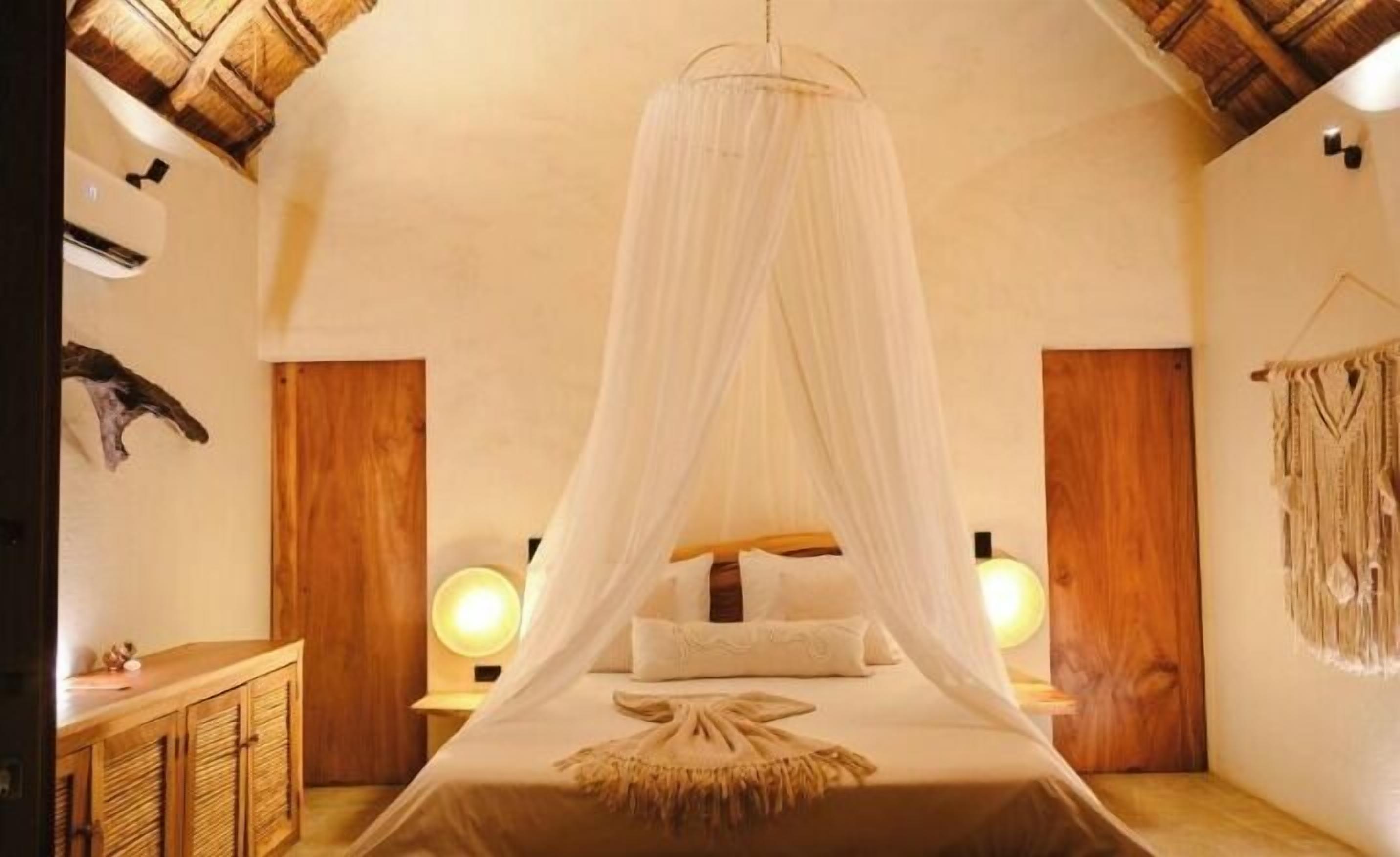 A room with a canopy bed, wooden walls, a wooden cabinet, and a wall-mounted lamp.