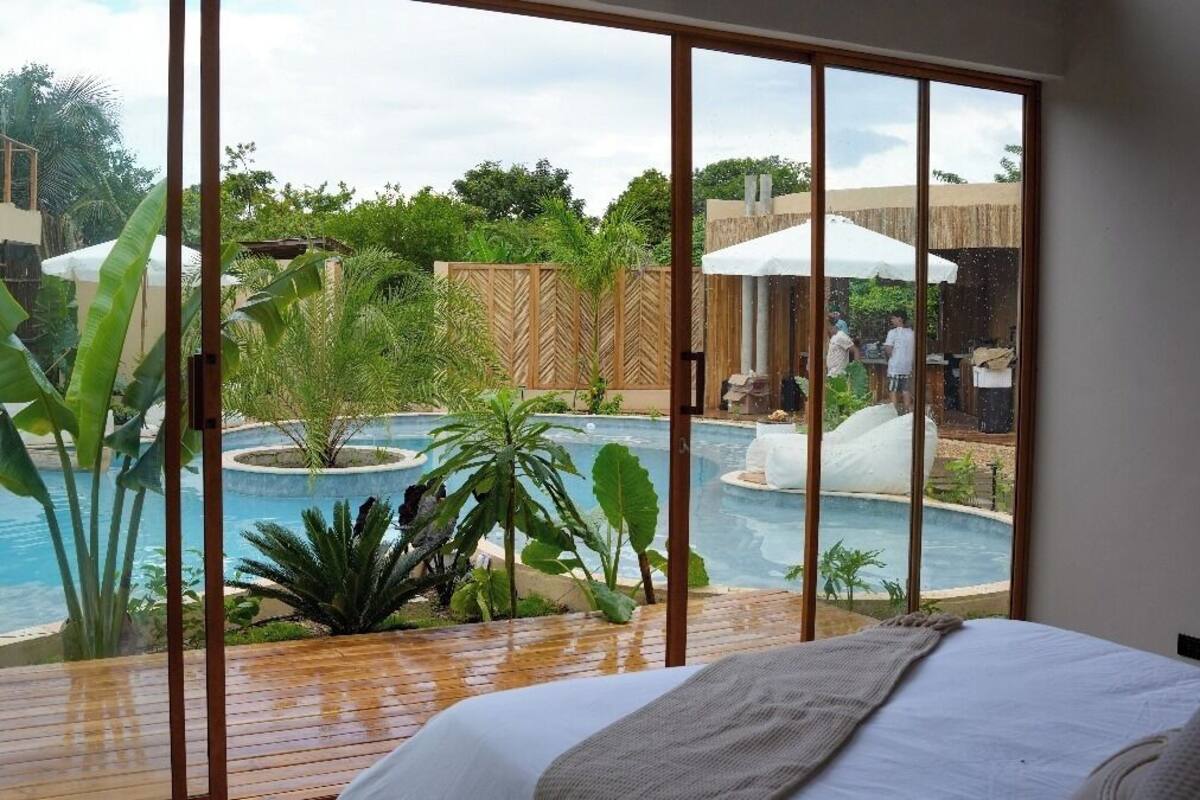 Un dormitorio con un ventanal grande con vistas a una zona de piscina.