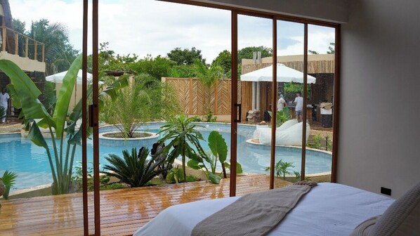 A bedroom with a large window overlooking a pool area. - VelaNova Paradise - HotelRetreat (Cartagena)